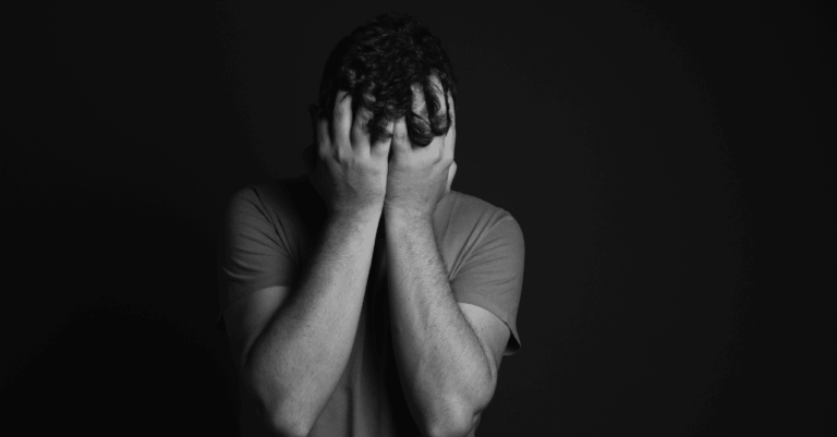 Black and white image of a man holding his head due to nervousness, covering hhead with hands