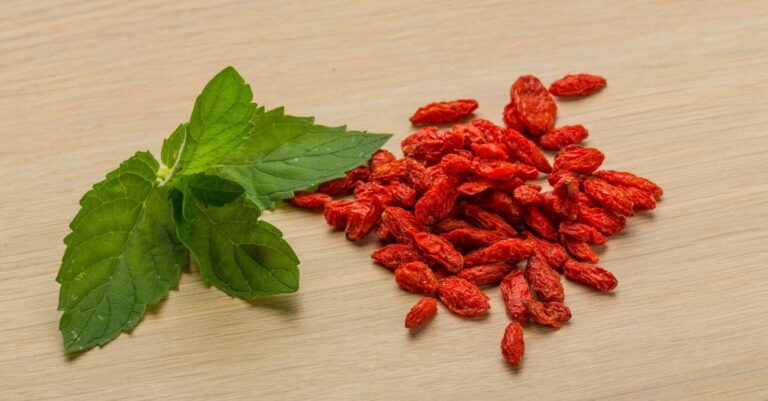 Goji berries and leaves on a wooden surface, resembling 'Can Berberine Damage the Liver'.