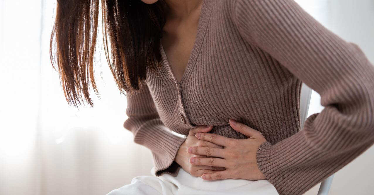 A woman experiencing stomach ache resembling how to restore gut health after stomach flu