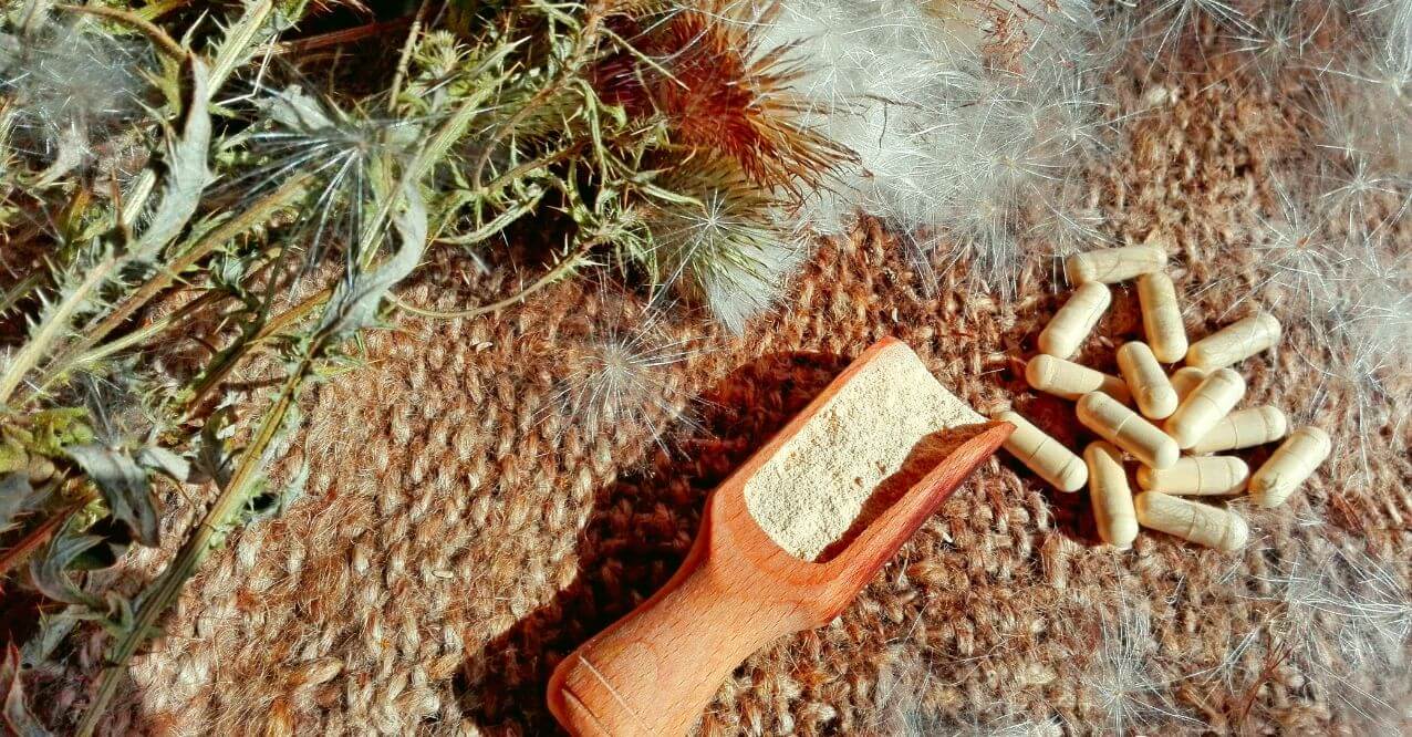 capsules and dried herbs on a wooden surface, resembling 'What Medications Should Not Be Taken With Milk Thistle'.