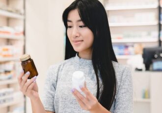 A woman holding two different supplement bottles, resembling 'Magnesium Citrate vs Glycinate'.